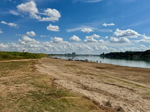 Joen rantaa, kalastajia ja uimareita